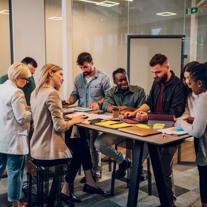 A group of people having a meeting at a table, talking and smiling