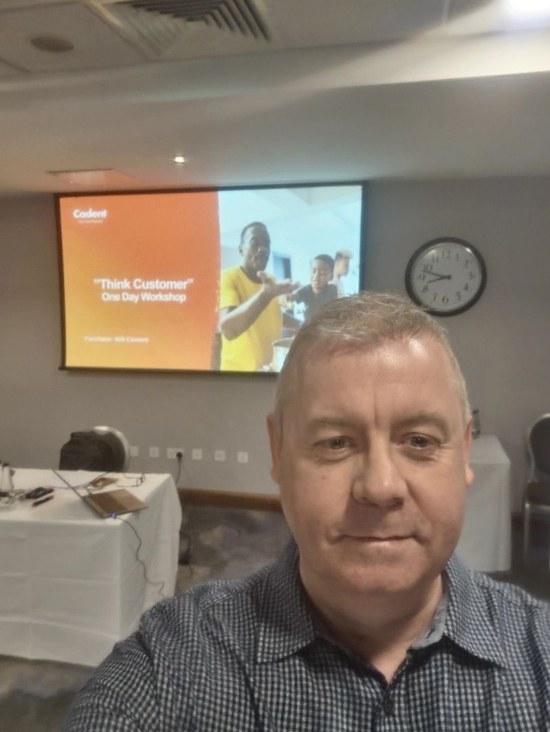 Man stood in front of a presentation screen that reads ' 