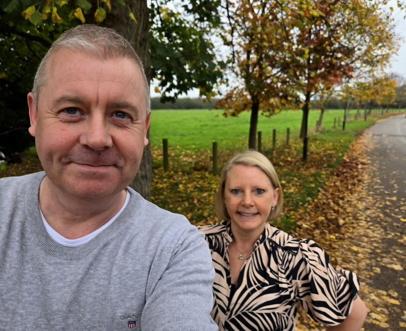 Man stood with a woman outside, in an autumnal setting